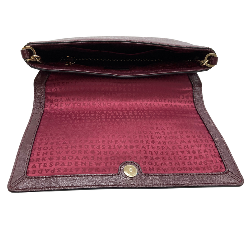 Load image into Gallery viewer, Kate Spade Burgundy Leather Clutch - handbag with a sophisticated design. The bag is crafted from textured leather and features a flap closure with a gold-tone Kate Spade logo plate on the front.
