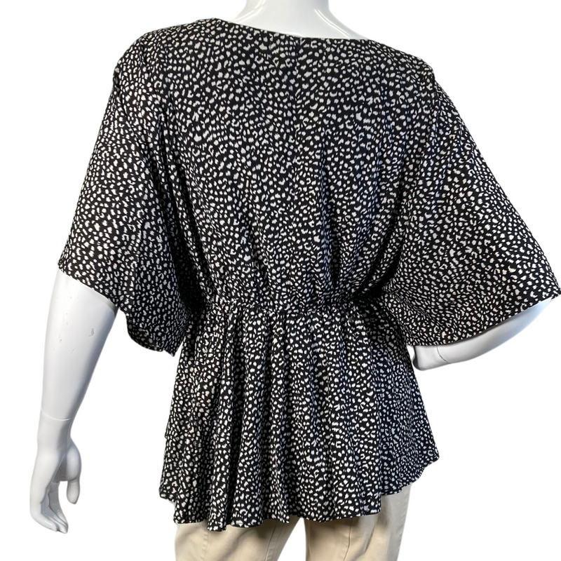 Load image into Gallery viewer, Eden In Love Polka Dot Black and White Blouse is a stylish, flowy black and white blouse featuring an abstract dotted pattern - backside view
