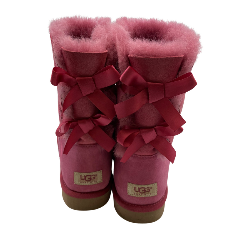 Load image into Gallery viewer, UGG Pink Boots with a Cute Bows in a vibrant pink shade, featuring a suede exterior and plush sheepskin lining for warmth and comfort - backside view featuring pink bows
