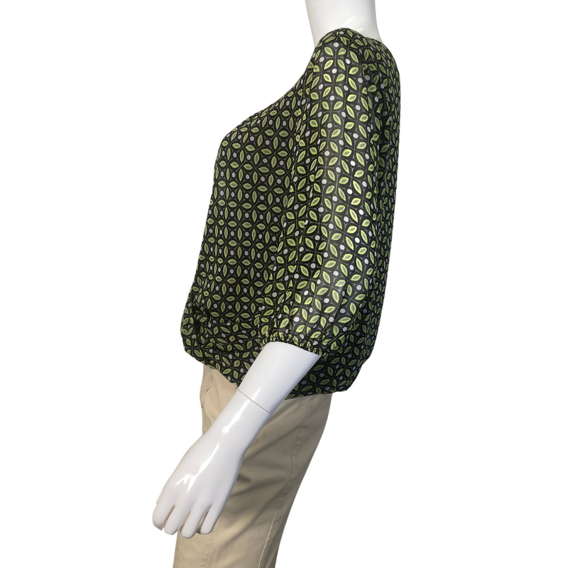 Load image into Gallery viewer, Vince Camuto Sheer Blouse with Opened V-shaped Cutout is a stylish women’s blouse featuring a unique geometric pattern in shades of green and black - side view
