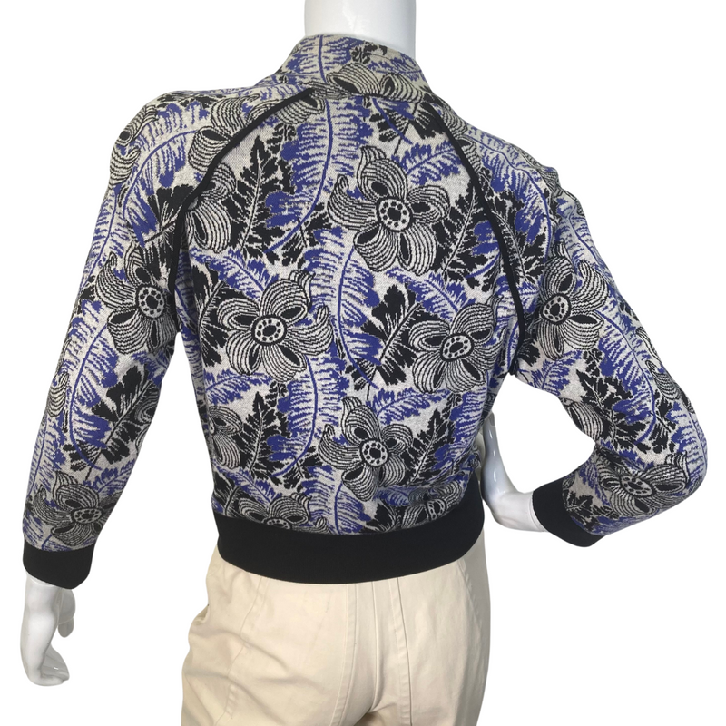 Load image into Gallery viewer, uicy Couture Abstract floral Jacket in black, blue and White with Gold Threading is a stylish, fitted jacket with a vibrant floral and botanical print in shades of blue, green, and purple - backside view
