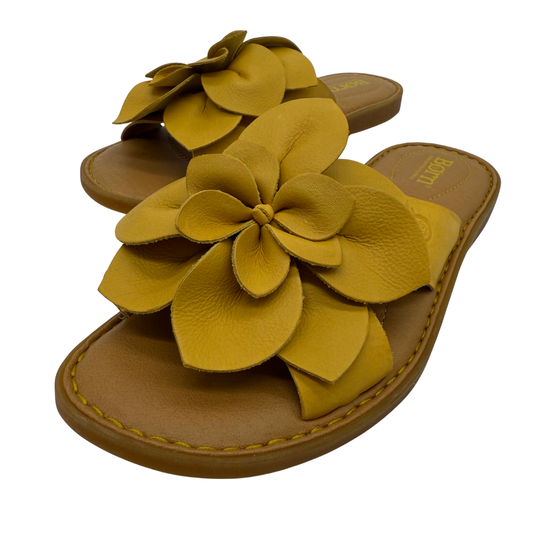 Pair of sandals with yellow flower details on a white background