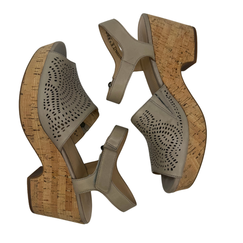 Pair of beige high-heeled shoes with cork platforms on a white background