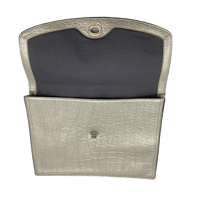 Load image into Gallery viewer, This pre-loved Coach Champagne Gold Clutch item is a metallic silver clutch bag with a textured finish resembling crinkled leather. It features a flap closure secured by a twist-lock mechanism, giving it a sleek and elegant look.
