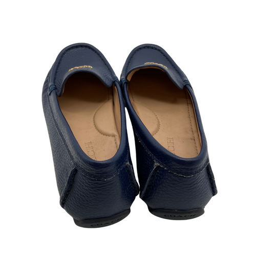 Coach Blue Leather Flats are sleek black leather loafers by Coach, featuring a pebbled texture and a slip-on design for comfort and convenience.