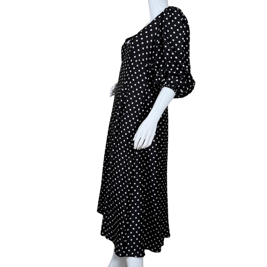 Black dress with white polka dots on a mannequin against a white background