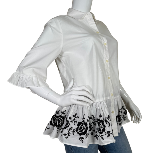 White blouse with black floral embroidery on a mannequin against a white background