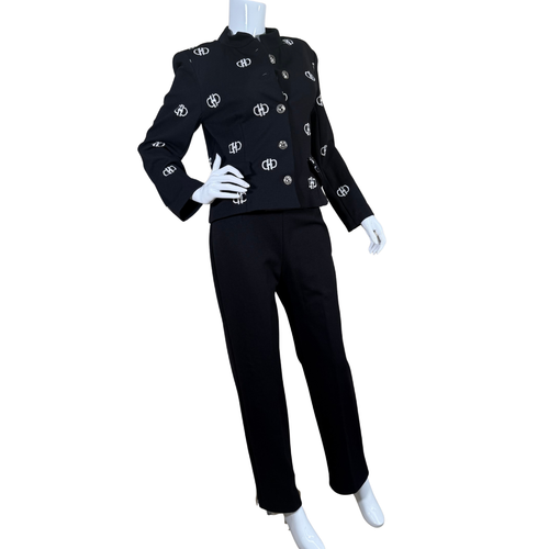 Nouritano Elegant Black Suit Set With White Embroideryt blends classic tailoring with playful branding, featuring a cropped jacket adorned with silver-tone logo embellishments throughout.