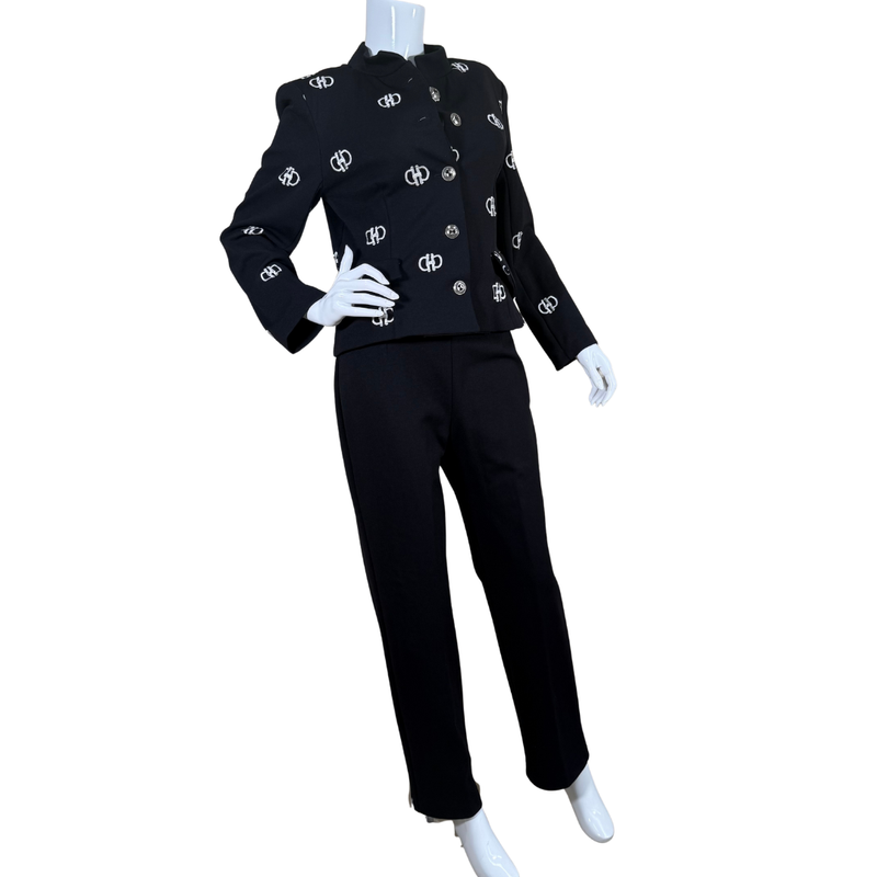 Load image into Gallery viewer, Nouritano Elegant Black Suit Set With White Embroideryt blends classic tailoring with playful branding, featuring a cropped jacket adorned with silver-tone logo embellishments throughout.
