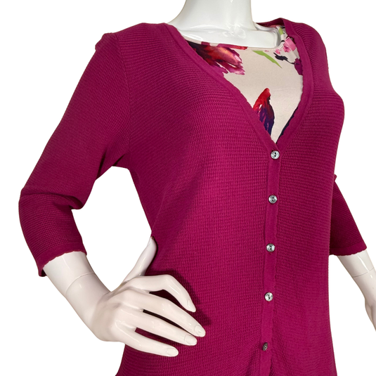 Mannequin wearing a pink cardigan over a floral top on a white background