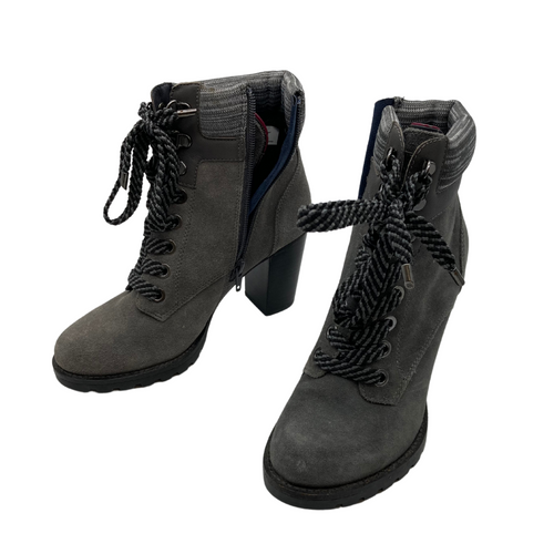 Tommy Hilfiger Grey Heel Boots are trendy heeled ankle boots with a rugged yet stylish design. They feature a lace-up front with bold, thick laces for an edgy look, complemented by a side zipper for easy wear.