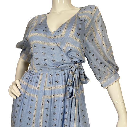 Urban Outfitters Baby Blue Wrap Like Midi Dress is a charming light blue, knee-length wrap dress with a delicate white and navy geometric print