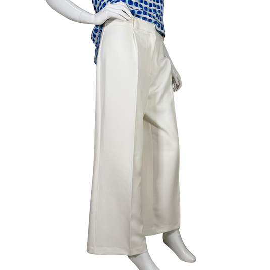 Mannequin wearing a blue top with white polka dots and white wide-leg pants on a white background