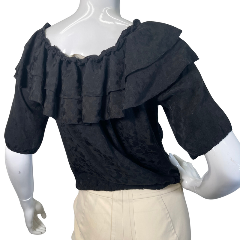 Load image into Gallery viewer, This pre-loved Zadig &amp; Voltaire Black Ruffle Blouse is a vintage-inspired short-sleeve blouse with layered ruffle details along the neckline, button-down front, and an adjustable drawstring waist for a flattering fit - backside view
